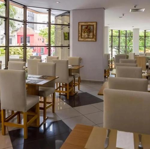 FLAT no Gonzaga com estacionamento incluso في سانتوس: غرفة طعام مع طاولات وكراسي ونوافذ