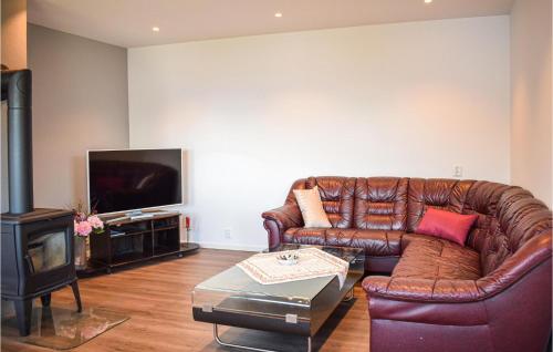 a living room with a leather couch and a television at 2 Bedroom Cozy Apartment In Bjordal in Bjordal