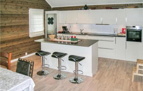 una cocina con armarios blancos y una barra con taburetes en Lovely Home In Straumgjerde With House Sea View en Brunstad