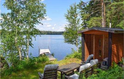 a cabin with a table and chairs next to a lake at Cozy Home In Högsby With Sauna in Aboda