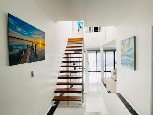 a staircase in a house with a painting on the wall at Sealand Lake House Stunning Absolute Waterfront in Fishing Point