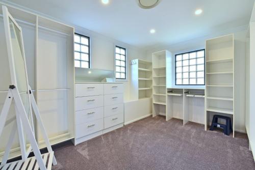 a walk in closet with white cabinets and windows at Sealand Lake House Stunning Absolute Waterfront in Fishing Point