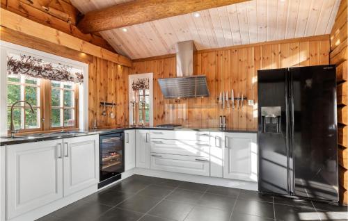 a kitchen with white cabinets and a black refrigerator at Gorgeous Home In Lampeland With Kitchen in Lampeland