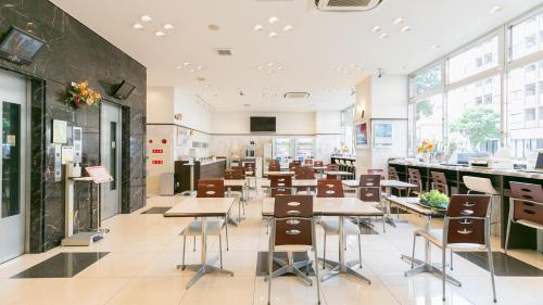 a cafeteria with tables and chairs and windows at Toyoko Inn Shizuoka eki Minami guchi in Shizuoka