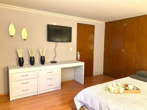 a bedroom with a white dresser with a tv on the wall at Cozy Stylish room in Polanco in Mexico City