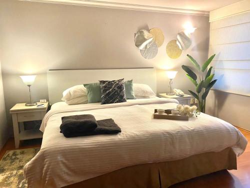 a bedroom with a large white bed with two lamps at Cozy Stylish room in Polanco in Mexico City