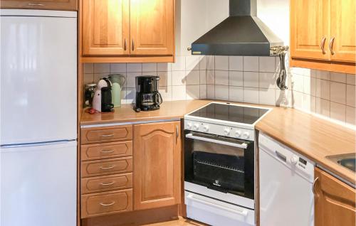 a kitchen with wooden cabinets and a white stove top oven at Amazing Home In Mönsterås With Kitchen in Mönsterås