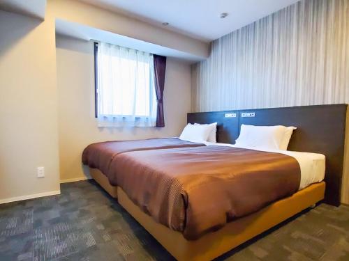 a bedroom with a large bed in a room at HOTEL LiVEMAX Tachikawa Ekimae in Tachikawa