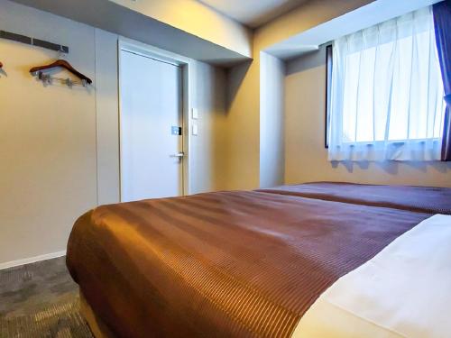 a bedroom with a large bed and a window at HOTEL LiVEMAX Tachikawa Ekimae in Tachikawa