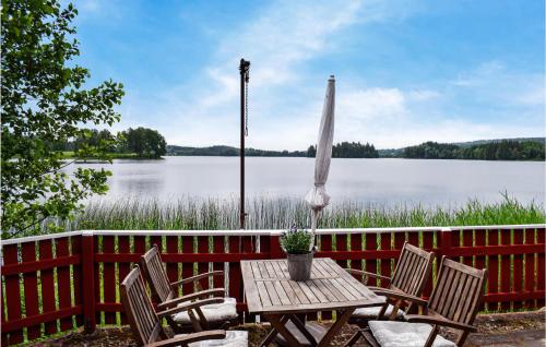 a wooden table with chairs and an umbrella in front of a lake at 2 Bedroom Gorgeous Home In Bottnaryd in Bottnaryd