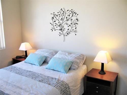 a bedroom with a bed with blue pillows at Toowoon Beach View 3br Villa 4 just steps to beach in The Entrance