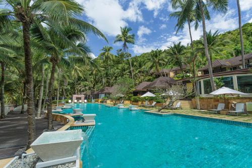 a pool at a resort with palm trees at Andaman White Beach Resort - SHA Plus in Nai Thon Beach