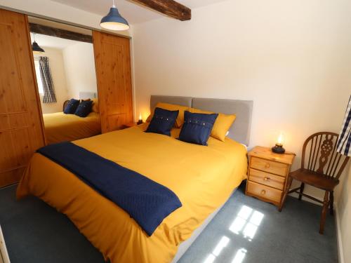 a bedroom with a large yellow bed and a chair at Mortons Cottage in Castlemorton