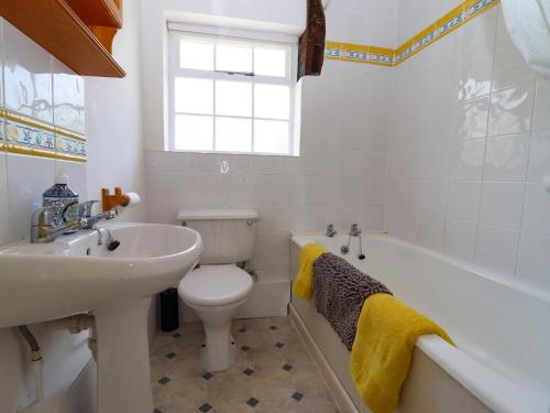a bathroom with a sink and a toilet and a bath tub at Mortons Cottage in Castlemorton