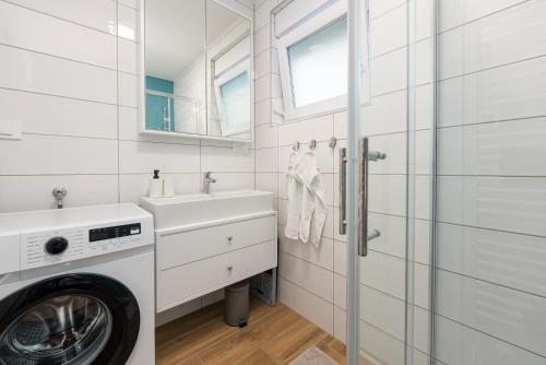 a white bathroom with a washing machine and a sink at Apartmani Diva in Zadar