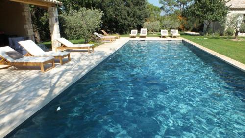 a swimming pool with lounge chairs in a backyard at Mas Notre Dame in Eygalières