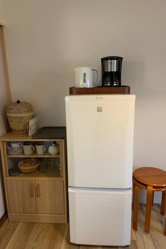 a white refrigerator in a kitchen next to a cabinet at Kyoto Osaka SUMIREYA in Takatuki