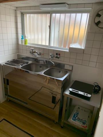 a kitchen with a sink and a counter with a window at Kyoto Osaka SUMIREYA in Takatuki