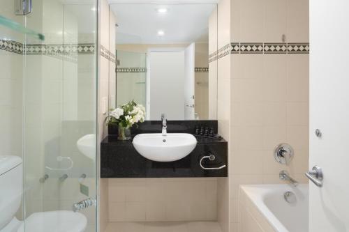 a bathroom with a sink, toilet and mirror at Rydges World Square in Sydney