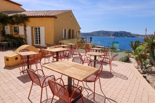 a patio with tables and chairs with a view of the water at Le Saint Erasme, Hotel Eco Friendly in Calvi