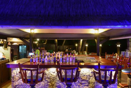 um bar com um monte de garrafas e cadeiras em Andaman White Beach Resort - SHA Plus em Praia de Nai Thon