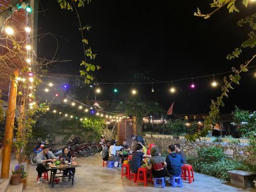 a group of people sitting at tables in a garden at night at Meo Vac Valley in Mèo Vạc