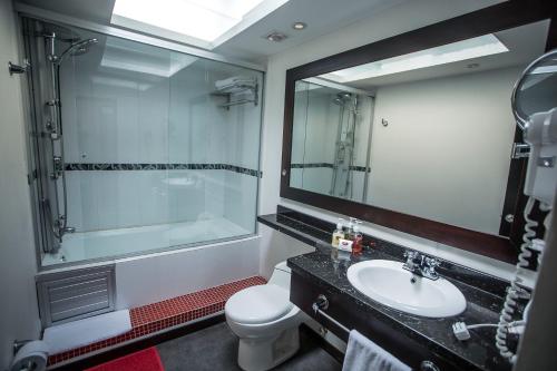 a bathroom with a sink and a toilet and a mirror at Europa Hotel Boutique Manizales in Manizales