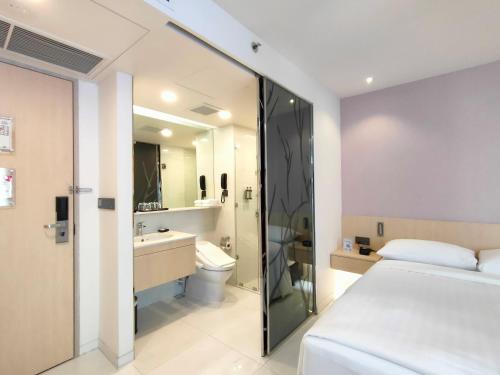 バンコクにあるエーワーグリーン　ラーローホテル（バンコク）のベッドとバスルーム付きのホテルルームです。