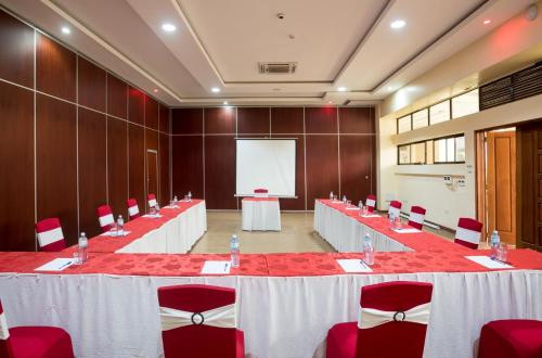 a conference room with tables and red chairs and a screen at Verona Hotel and Conference Center in Ruiru