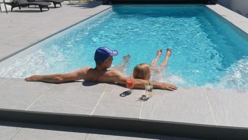 a man and a girl in a swimming pool at Logis Le Printemps Hôtel Restaurant - Montélimar in Montélimar