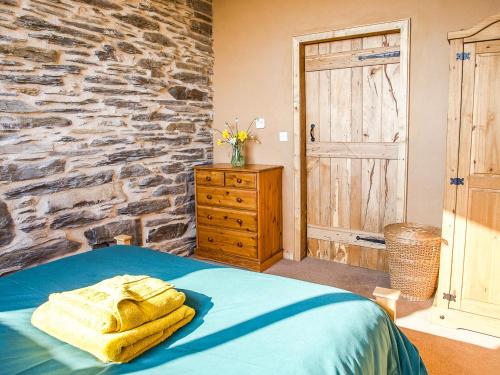 a bedroom with a bed and a stone wall at Tyn Llwyn Cornel Eco Barn in Penrhyndeudreath