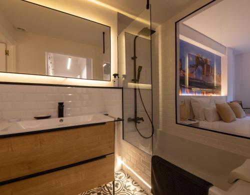 a bathroom with a sink and a mirror and a bed at Bilbao Henao Park de Bilbao Suites, en pleno centro con garaje directo in Bilbao