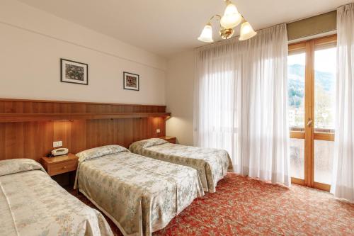 a hotel room with two beds and a window at Albergo Belvedere in Fiera di Primiero