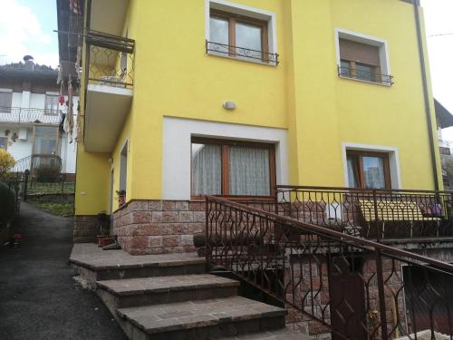 a yellow house with stairs in front of it at RESIDENZE DOLOMITICHE la casa gialla in Calalzo