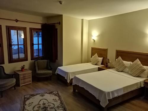 a hotel room with two beds and a chair at Casa Callinos in Selcuk