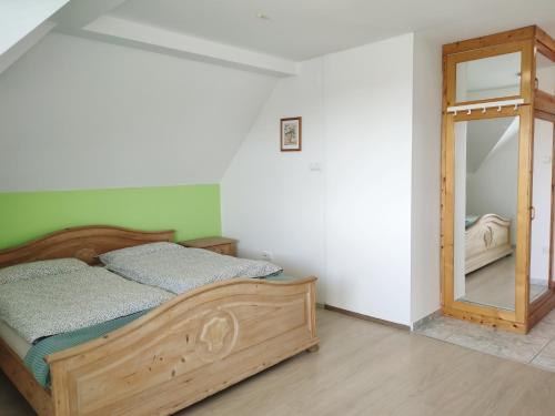 1 dormitorio con cama de madera y espejo en Szandra Apartmanház, en Gyenesdiás