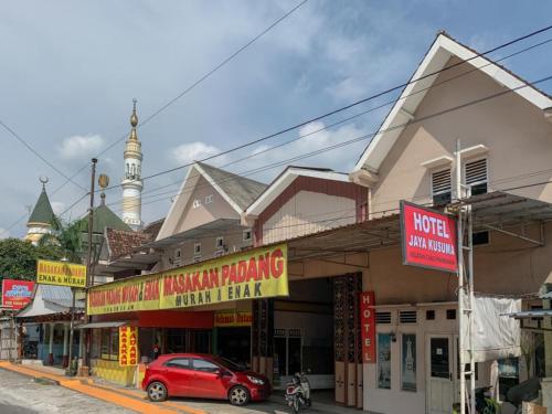 a street with a red car parked in front of a building at Hotel Jaya Kusuma near Candi Prambanan Mitra RedDoorz in Prambanan