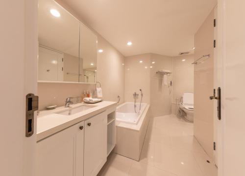 a white bathroom with a sink and a toilet at Centre Point Silom in Bangkok