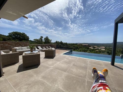 a patio with chairs and a swimming pool with a view at Tres belle villa neuve vue mer avec piscine chauffee in Sainte-Lucie de Porto-Vecchio