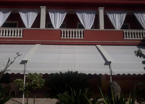 a balcony of a building with white curtains and plants at Mediterraneo B&B in Maglie