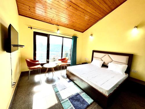 a bedroom with a bed and a table and chairs at NEELGAGAN RESORT in Chaukori