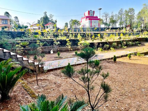 a garden with trees and a bridge in the background at NEELGAGAN RESORT in Chaukori