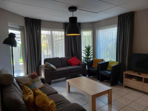 - un salon avec un canapé, des chaises et une table dans l'établissement Boszicht 1 appartement in Oostkapelle, à Oostkapelle