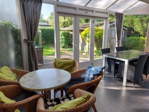 une terrasse couverte avec une table et des chaises dans l'établissement Boszicht 1 appartement in Oostkapelle, à Oostkapelle