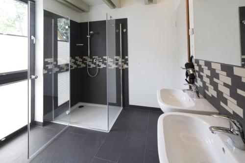 een badkamer met 2 wastafels en een glazen douche bij Domizil am Ostseewald - Seidelbast in Zingst