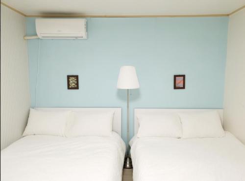two beds in a room with blue walls at House Mongja in Seoul