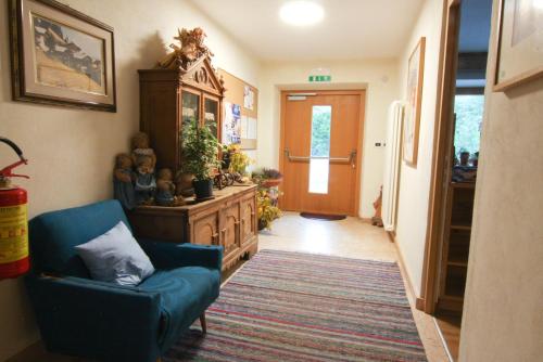 a hallway with a blue chair and a dresser in a room at Pension Enzian in Badia