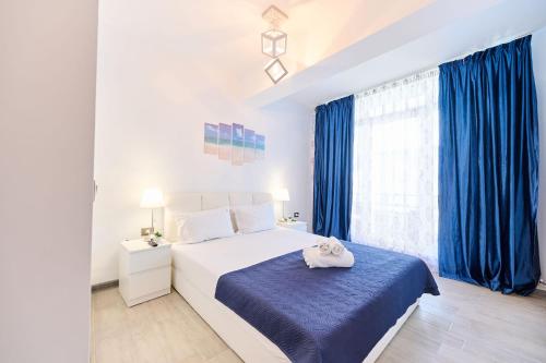 a white bedroom with blue curtains and a bed at Cermar Apartment- Spa n Pool beach resort- parking in Mamaia