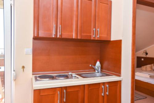a kitchen with a sink and wooden cabinets at Apartments Villa Sveti Nikola in Budva