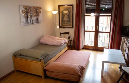 Cette chambre comprend un lit, une table et une fenêtre. dans l'établissement Bonita vivienda en el corazón de Zaragoza, à Saragosse